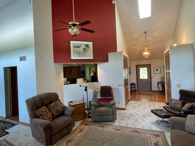 living room with high vaulted ceiling, hardwood / wood-style flooring, and ceiling fan with notable chandelier