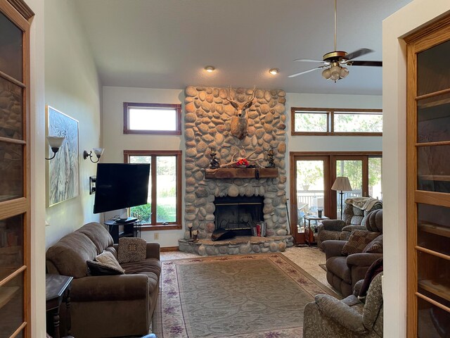 living room with ceiling fan, a fireplace, a towering ceiling, and a healthy amount of sunlight