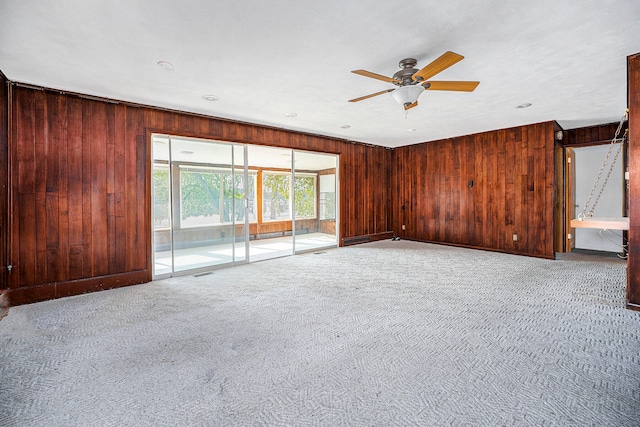 carpeted empty room featuring ceiling fan and wooden walls