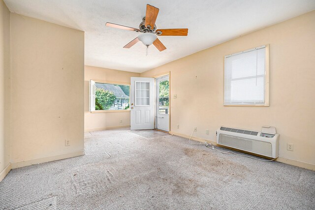 carpeted spare room with a wall mounted air conditioner and ceiling fan