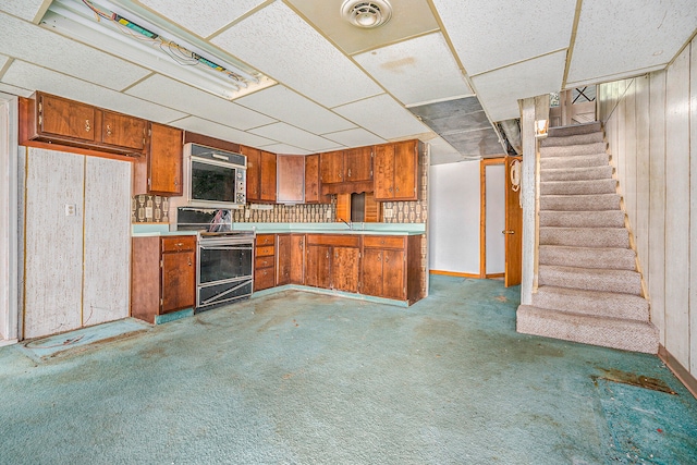 kitchen featuring decorative light fixtures, sink, electric stove, carpet, and wood walls