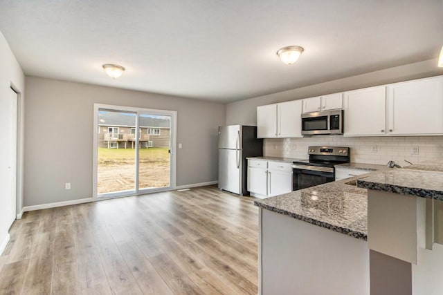 kitchen with sink, white cabinetry, stainless steel appliances, tasteful backsplash, and dark stone counters