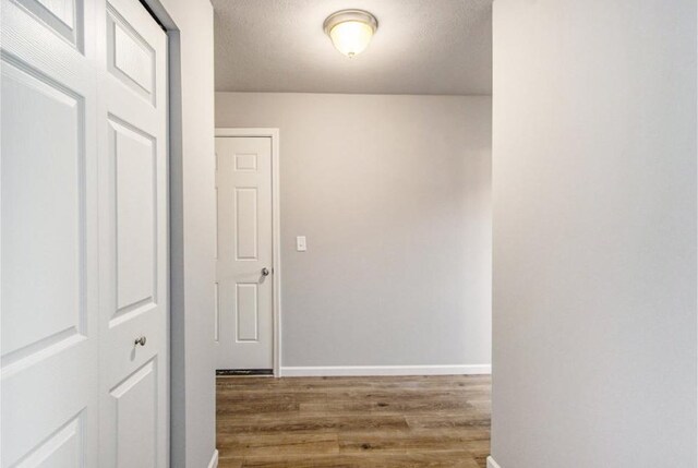 corridor with hardwood / wood-style floors and a textured ceiling