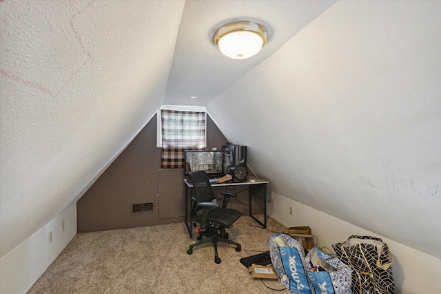 office space with vaulted ceiling, a textured ceiling, and light colored carpet