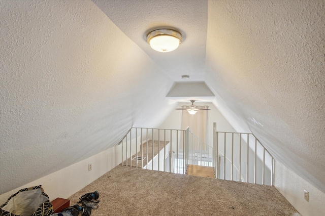 stairway with lofted ceiling, carpet flooring, ceiling fan, and a textured ceiling