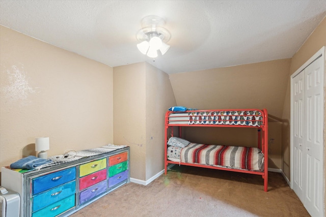 carpeted bedroom with a textured ceiling, ceiling fan, and a closet