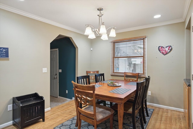 dining room with crown molding, light hardwood / wood-style flooring, and an inviting chandelier