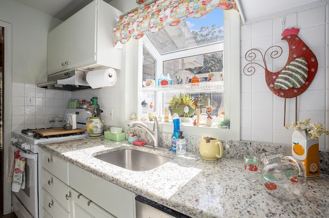 kitchen featuring light stone countertops, sink, gas range gas stove, and white cabinetry