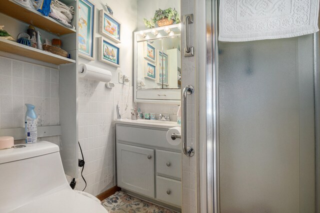 bathroom with tile walls, an enclosed shower, vanity, and toilet