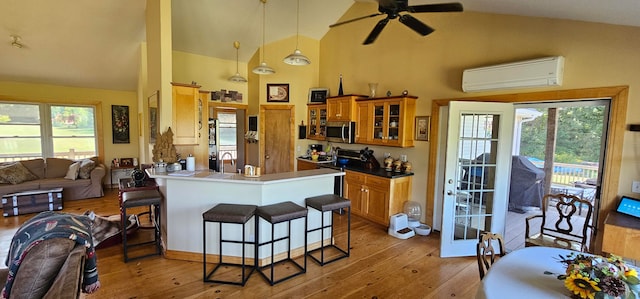 kitchen featuring plenty of natural light, light wood-type flooring, a wall unit AC, and kitchen peninsula