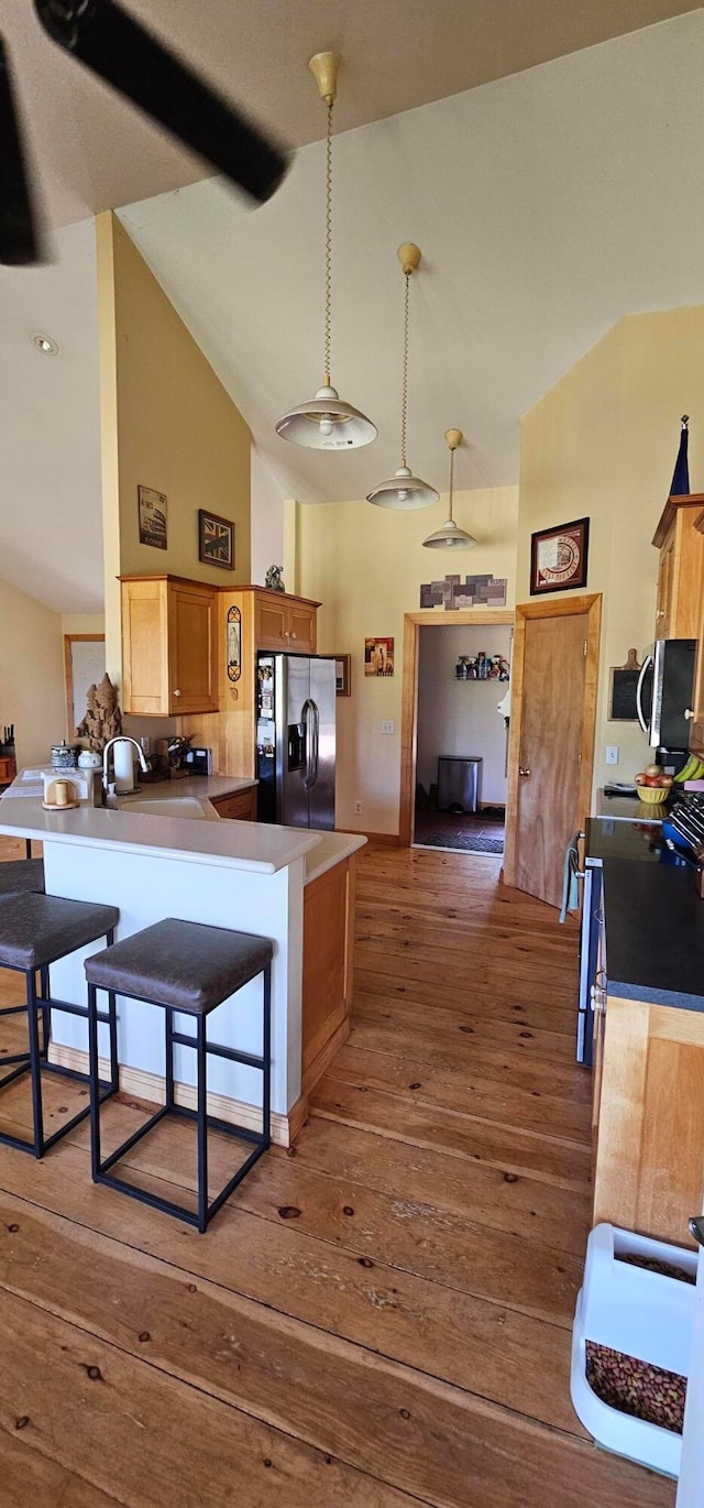 kitchen with appliances with stainless steel finishes, kitchen peninsula, a kitchen breakfast bar, and dark hardwood / wood-style flooring