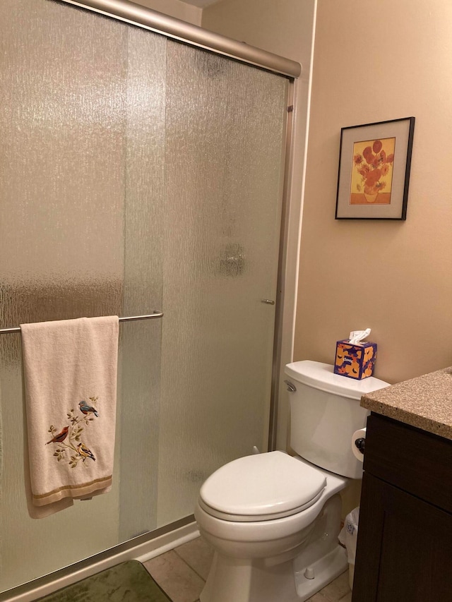 bathroom featuring tile patterned flooring, a shower with door, vanity, and toilet