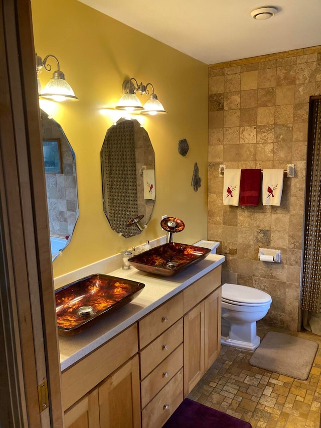 bathroom with vanity, tile walls, and toilet