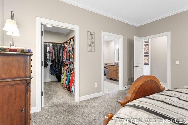 bedroom featuring a closet, light colored carpet, a walk in closet, and connected bathroom