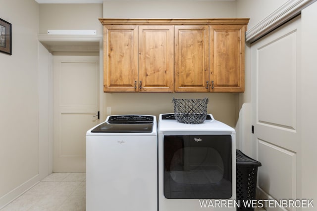 washroom with light tile patterned floors, cabinets, and washing machine and dryer