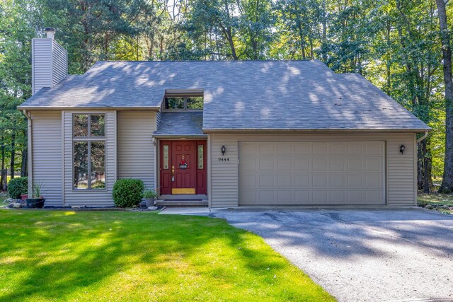 view of front facade featuring an attached garage, a chimney, a shingled roof, and a front lawn