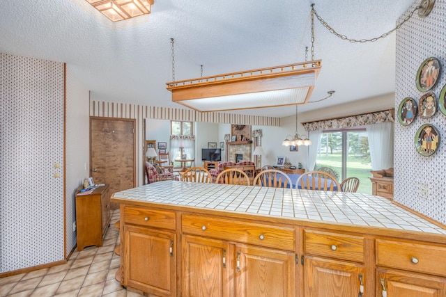 kitchen featuring tile countertops, decorative light fixtures, and a textured ceiling