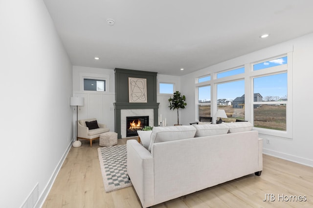 living room featuring a high end fireplace and light wood-type flooring