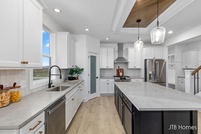 kitchen with pendant lighting, wall chimney range hood, sink, appliances with stainless steel finishes, and a kitchen island