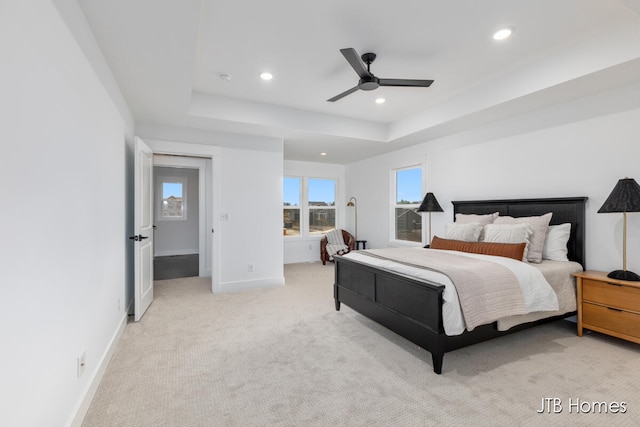 bedroom with light carpet, a raised ceiling, and ceiling fan