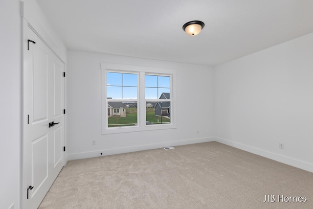 unfurnished room featuring light colored carpet