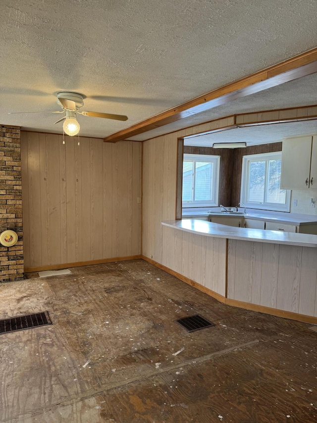 interior space featuring wood walls, sink, ceiling fan, and a textured ceiling