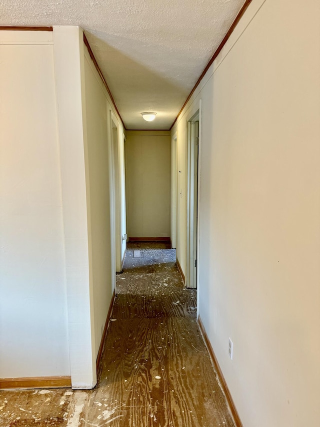 hall with a textured ceiling and crown molding