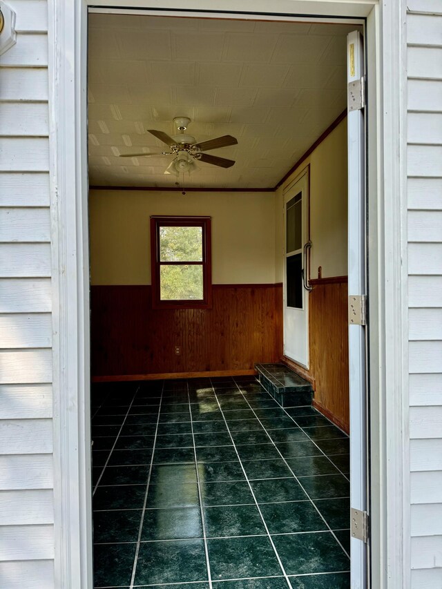 unfurnished room with ceiling fan and wood walls