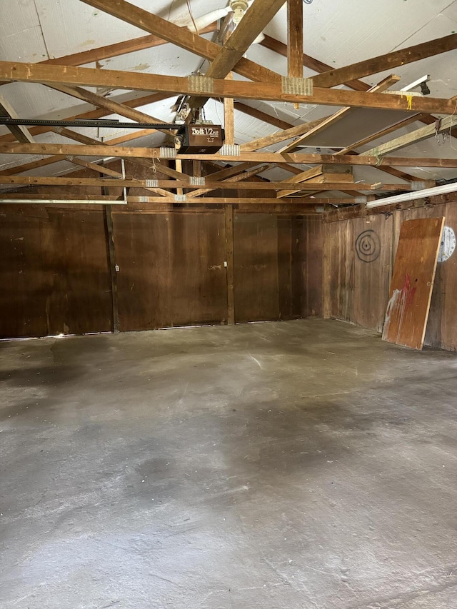 garage featuring a garage door opener and wooden walls