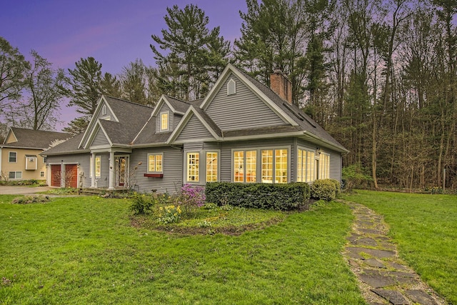 craftsman-style home featuring a garage, a front lawn, driveway, and a chimney