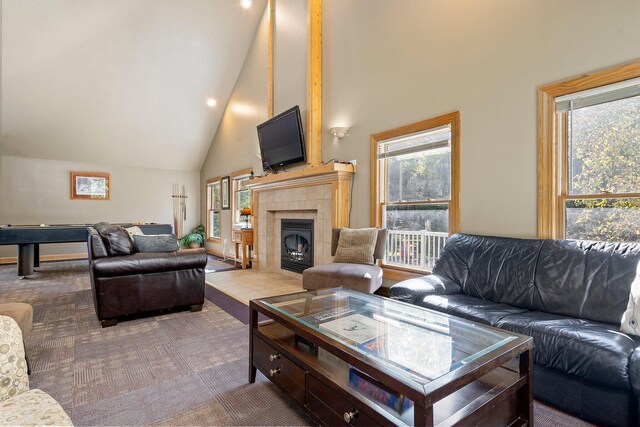 carpeted living room with high vaulted ceiling, a healthy amount of sunlight, and a tile fireplace