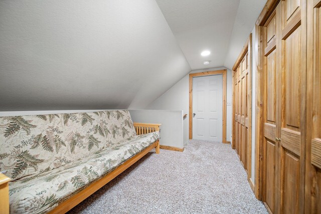 bedroom with two closets, carpet flooring, a textured ceiling, and vaulted ceiling