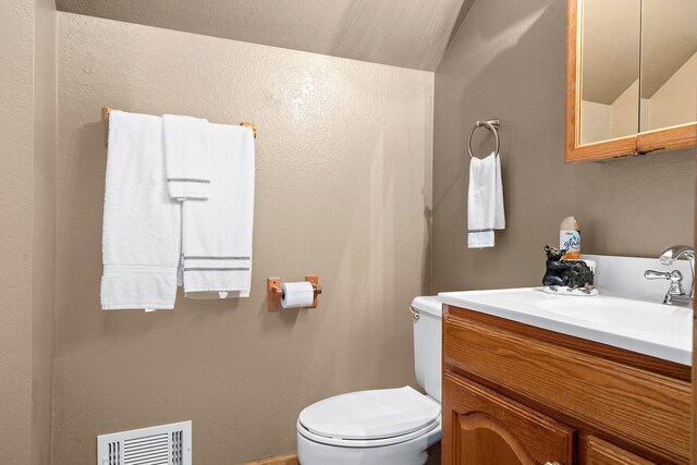 bathroom featuring lofted ceiling, vanity, and toilet