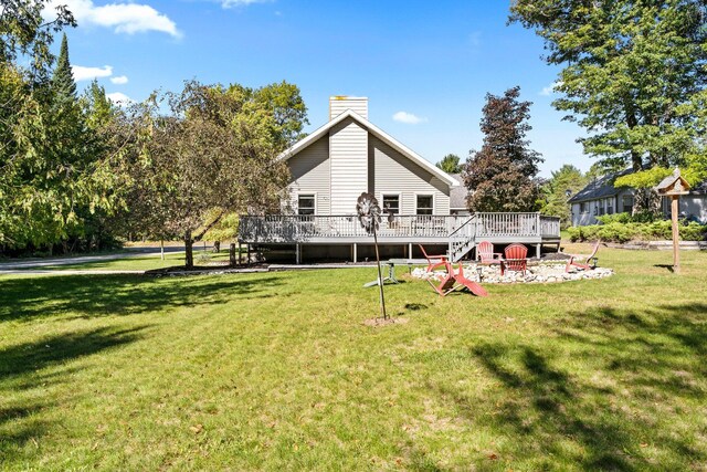 rear view of property with a wooden deck and a lawn