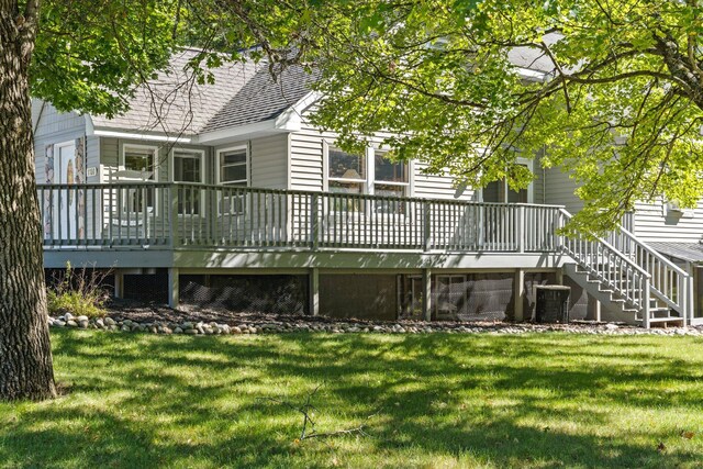 rear view of property featuring a lawn, a wooden deck, and central air condition unit