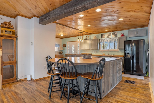 kitchen with gray cabinetry, hardwood / wood-style flooring, black refrigerator with ice dispenser, and wooden ceiling