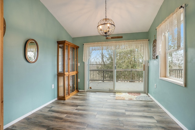 unfurnished dining area with an inviting chandelier, wood-type flooring, and lofted ceiling