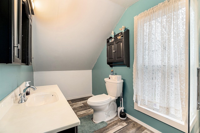 bathroom with wood-type flooring, vaulted ceiling, vanity, and toilet