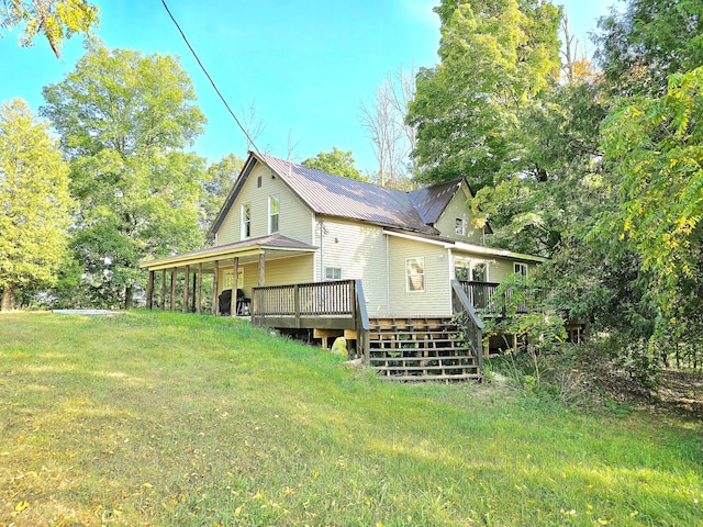 rear view of house featuring a deck and a lawn