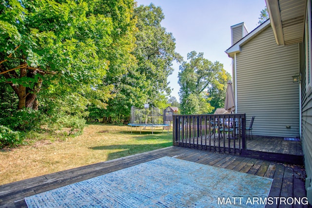 wooden terrace with a trampoline and a yard