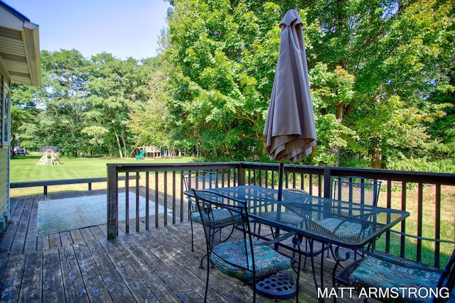 wooden deck with a playground and a yard