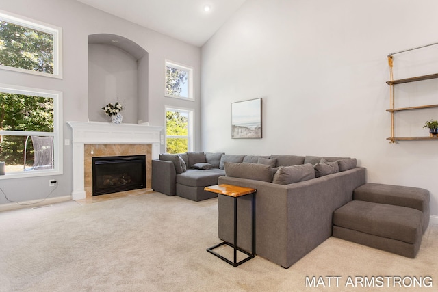 living room with a tiled fireplace, light carpet, and high vaulted ceiling