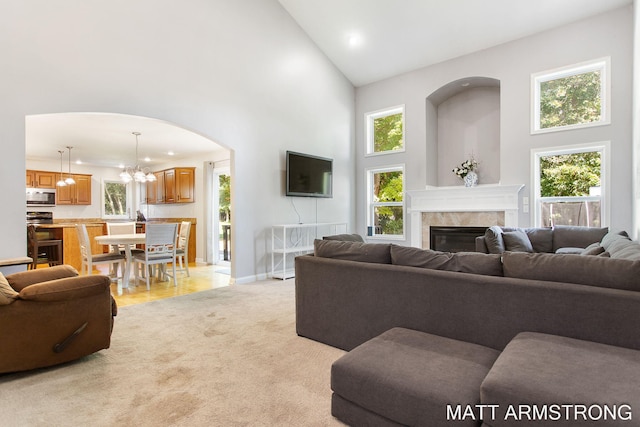 carpeted living room featuring a notable chandelier, high vaulted ceiling, and a fireplace