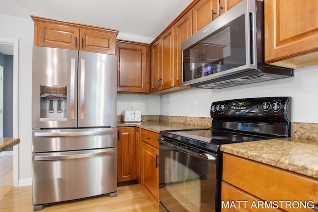 kitchen with light hardwood / wood-style flooring, light stone countertops, and appliances with stainless steel finishes