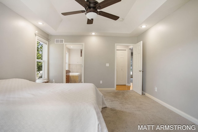 bedroom featuring a raised ceiling, ensuite bathroom, ceiling fan, and carpet floors