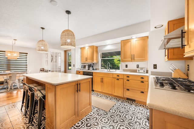 kitchen with a kitchen breakfast bar, a kitchen island, pendant lighting, range hood, and sink