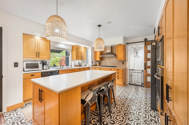 kitchen featuring hanging light fixtures, sink, a kitchen island, wall chimney exhaust hood, and a barn door