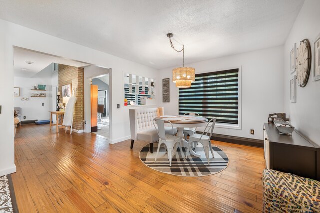 dining room featuring a notable chandelier, light wood-type flooring, and a textured ceiling