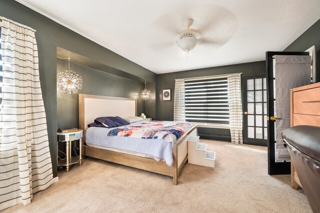 carpeted bedroom with a textured ceiling and ceiling fan with notable chandelier