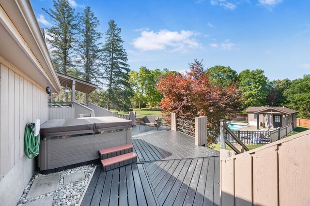 wooden terrace featuring a storage shed and a hot tub